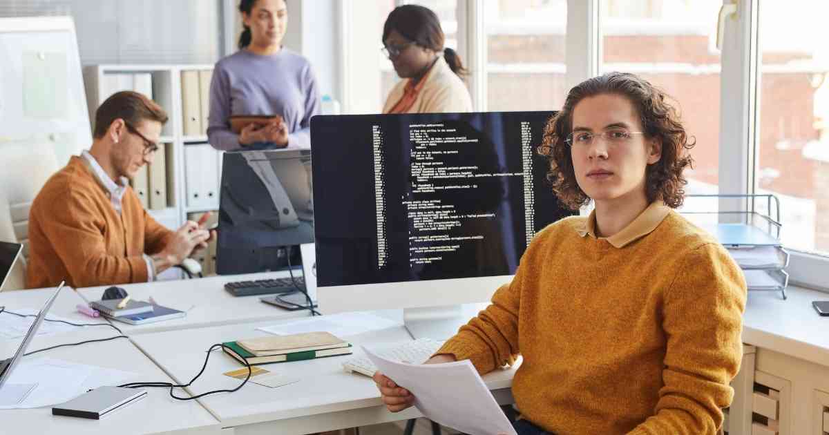 A group of people sitting at a desk in an office.